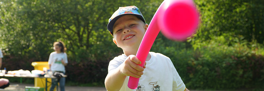 Ein Junge zeigt mit pinkem Plastikschlauch in die Kamera