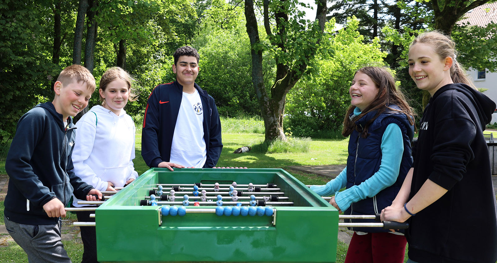 4 Kinder spielen Kicker, ein weiteres steht dabei