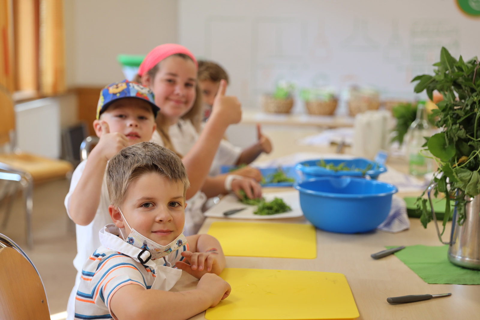 Kinder recken einen Daumen nach oben beim Kochen