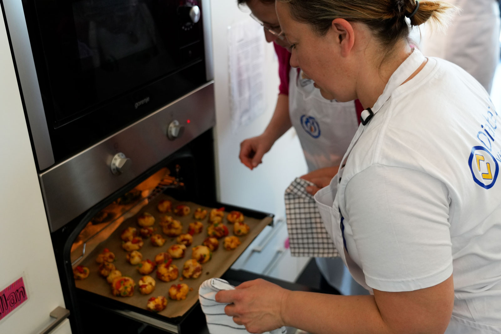 Zwei Frauen holen Pizzabällchen aus dem Ofen