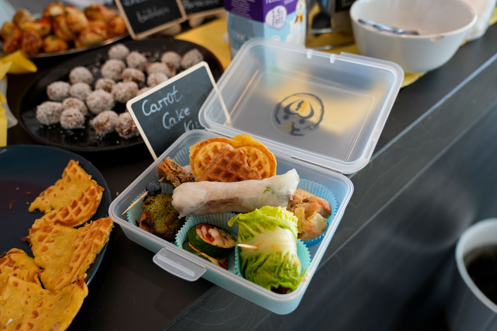 Eine gefüllte Lunchbox. Zu sehen sind u.a. Sommerrollen, Salatrollen und Waffeln
