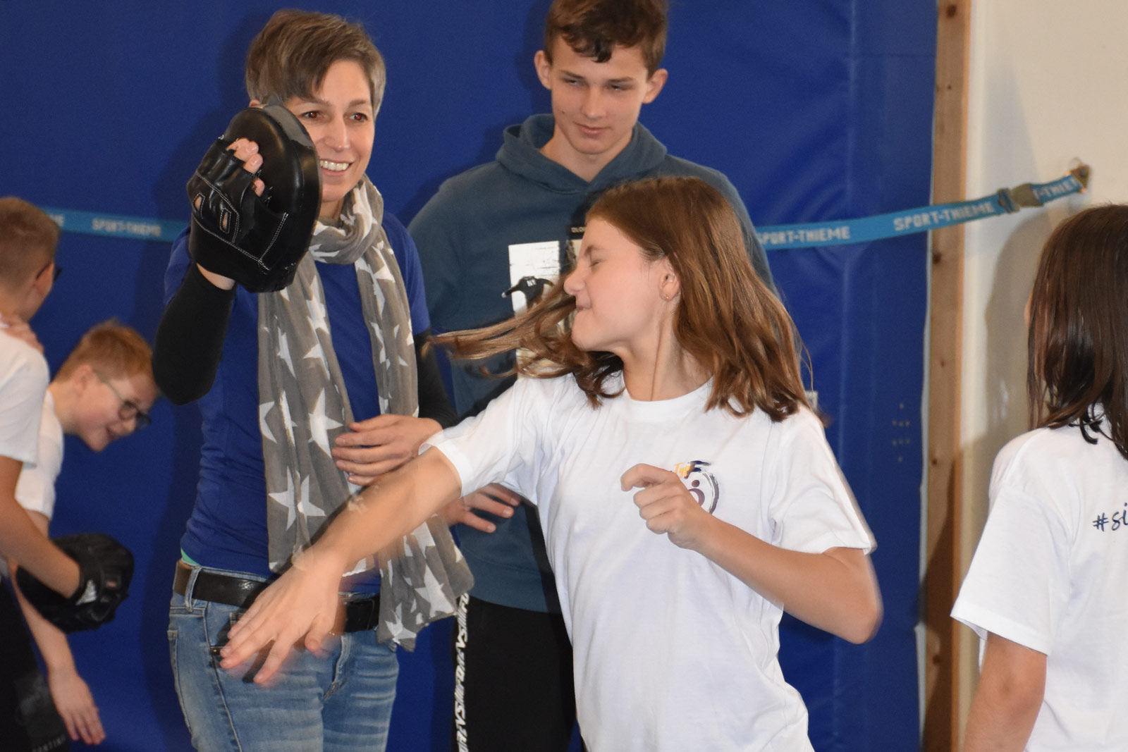 Ein Mädchen schlägt einen Schlagschutz aus Cladias Hand beiseite