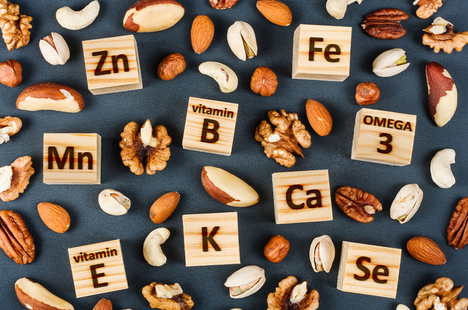 Holzbausteine mit Beschriftung unterschiedlicher Vitamineni Kleine Holzbausteine mit Buchstaben von verschiedenen Arten an Vitaminen und Mineralstoffen mit verschiedenen Sorten Nüsse