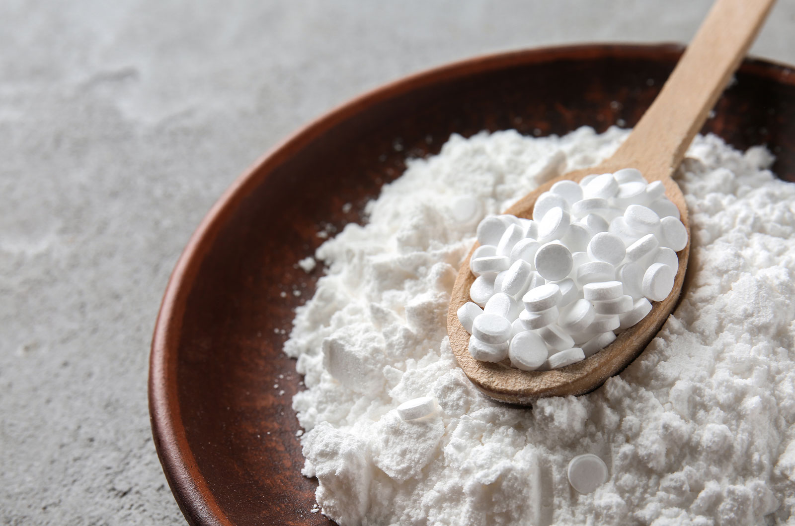 Zuckeraustauschstoffe in einer Schüssel und auf einem Holzlöffel