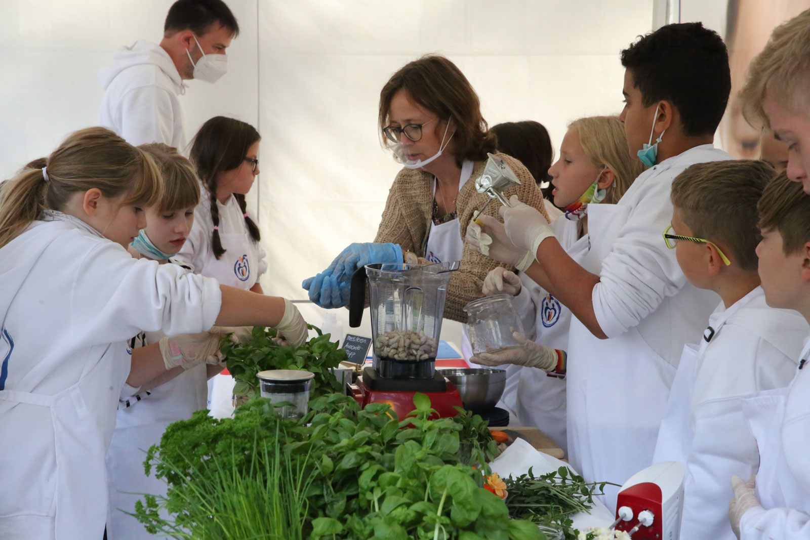 Regina Kröger bereitet an einem Tisch voller Kräuter mit Kinder Essen zu