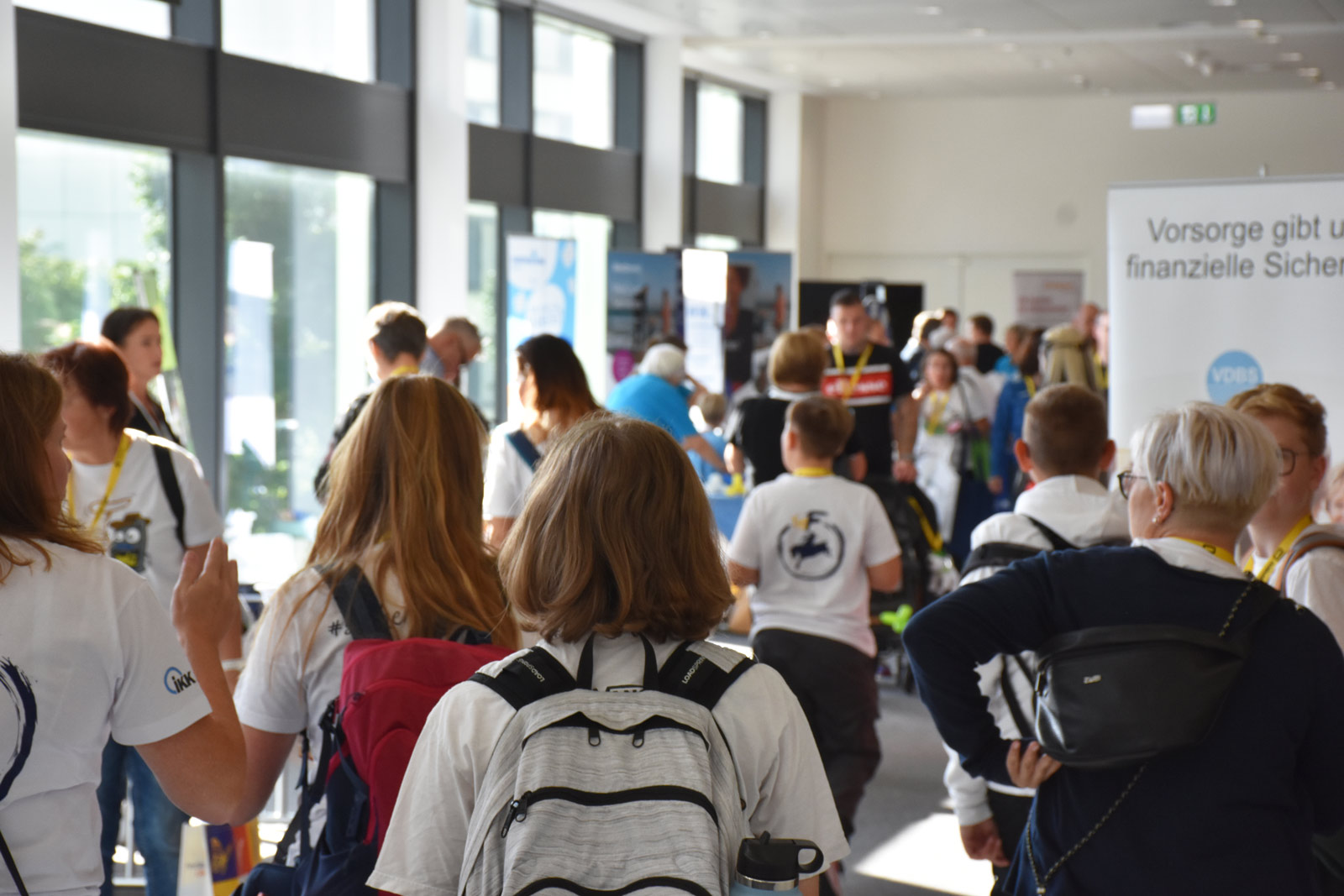 Eine Gruppe Menschen in Typ-F-Shirts schlendert durch die Messe