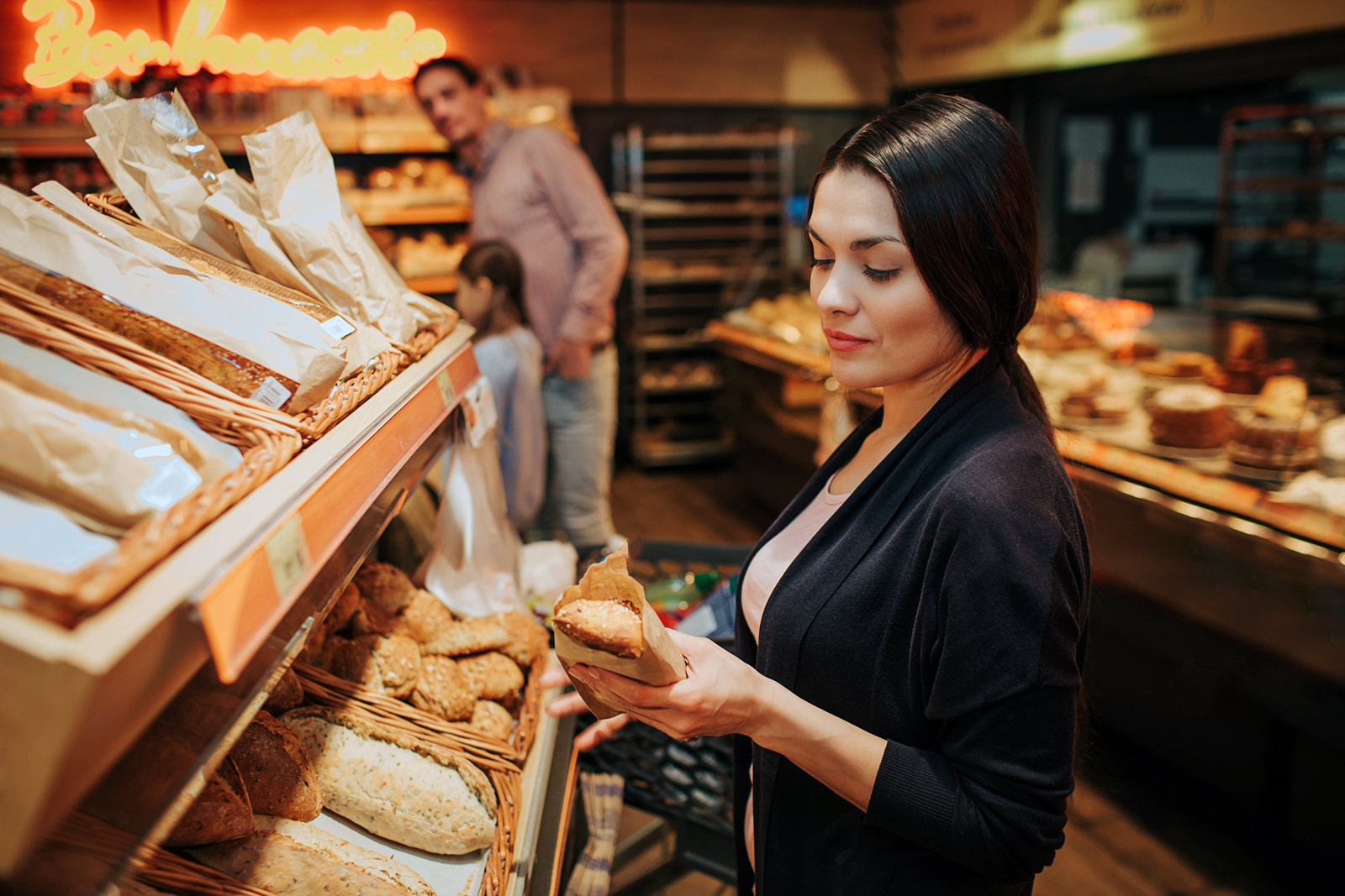 Eine Frau wählt Brot aus beim Bäcker.