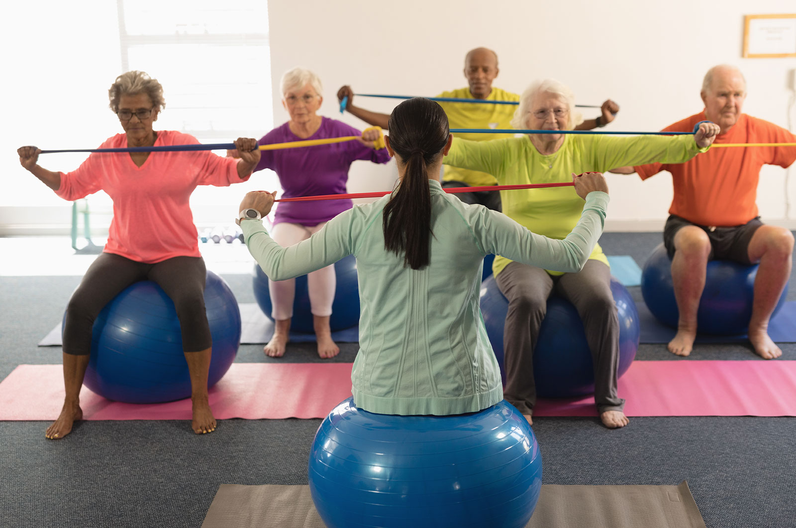 Senioren mit Trainerin beim Training mit Widerstandsband