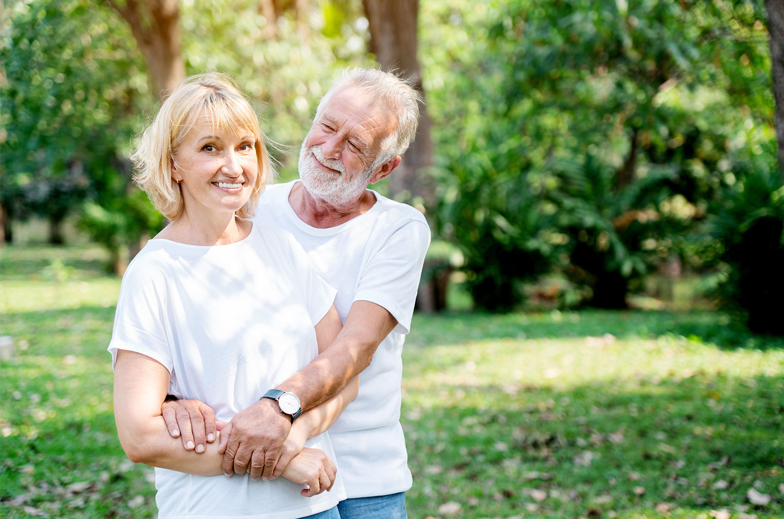 älteres Paar im Sommer im Garten, Mann kümmert sich um seine an Alzheimer erkrankte Partnerin