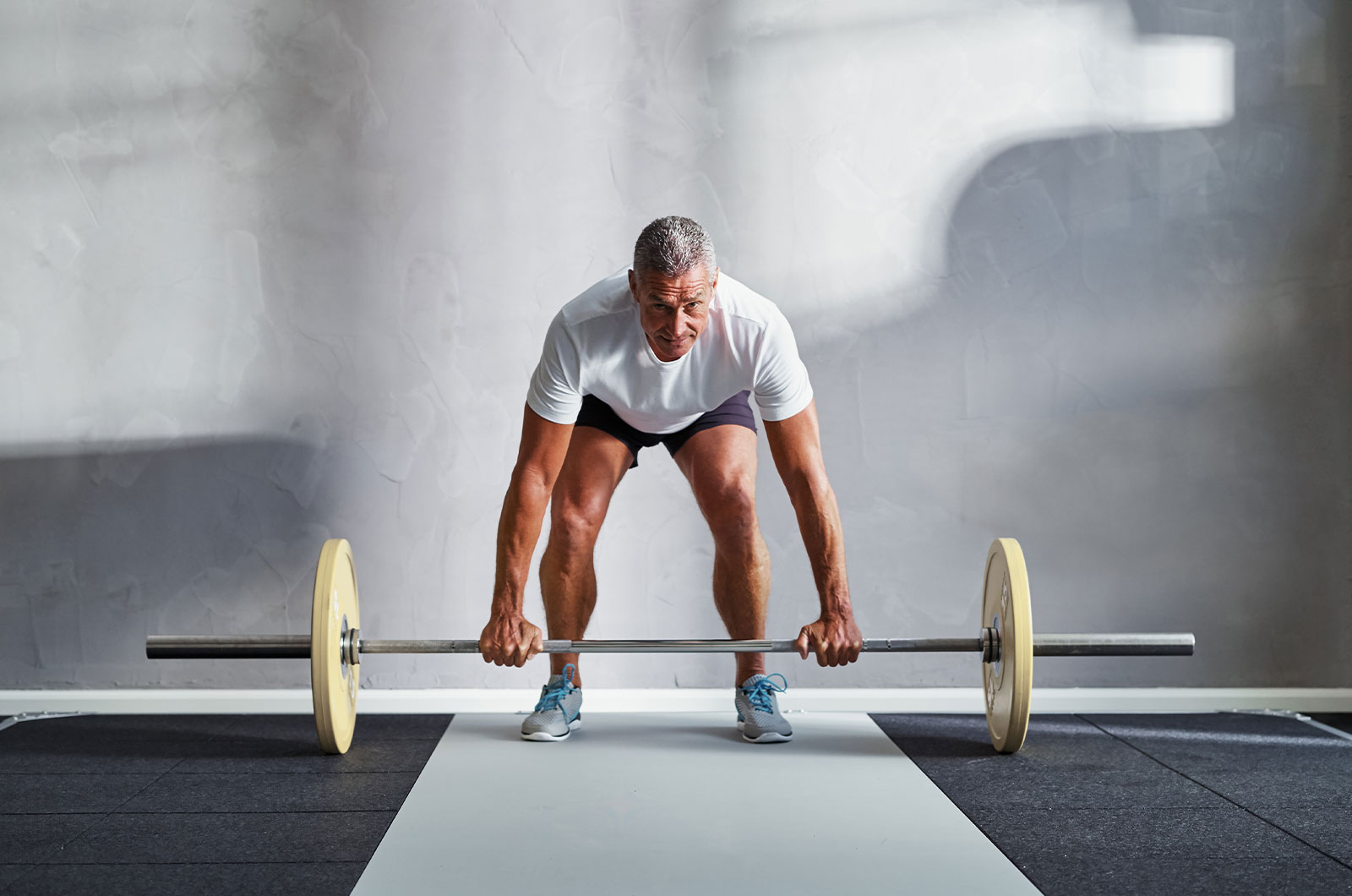 gut trainierter älterer Mann, der in einem Fitnessstudio Gewichte stemmt