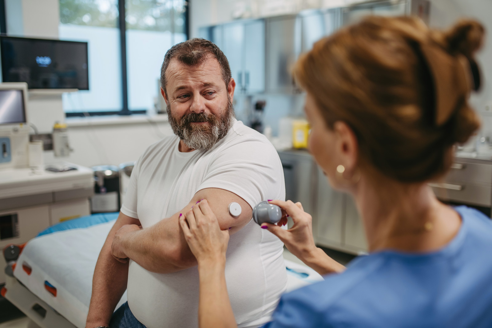 Ein Mann bekommt in einer Praxis einen CGM-Sensor gesetzt