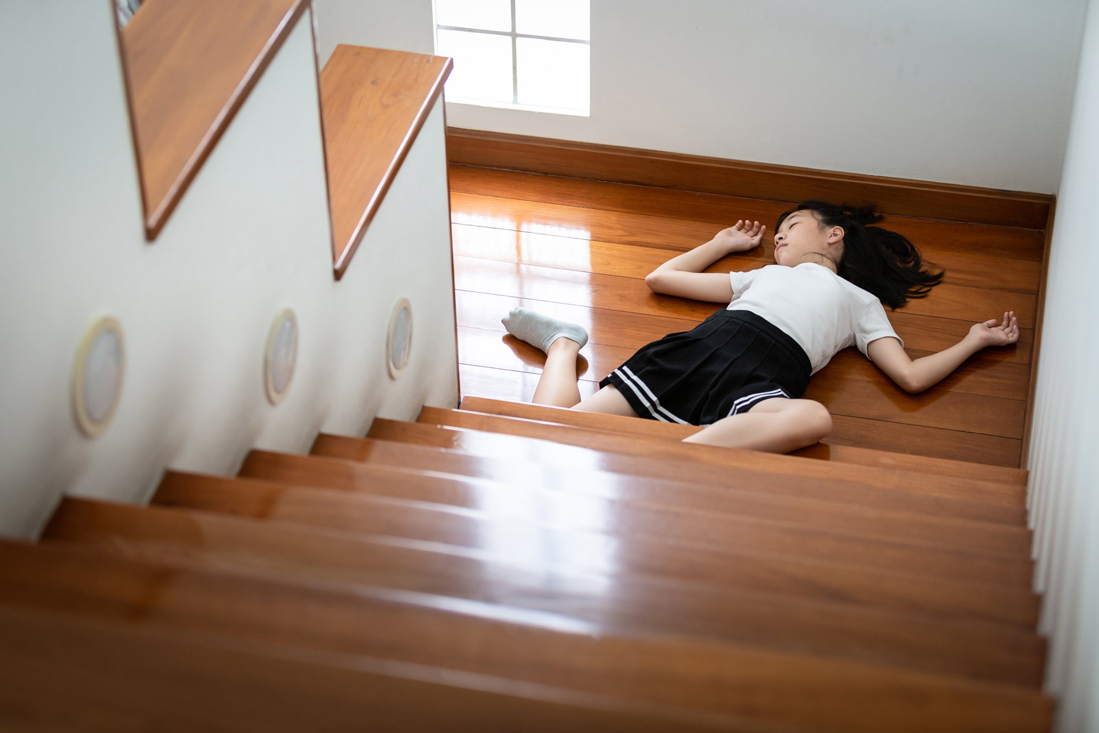 Ein kleines Mädchen liegt bewusstlos vor einer Treppe