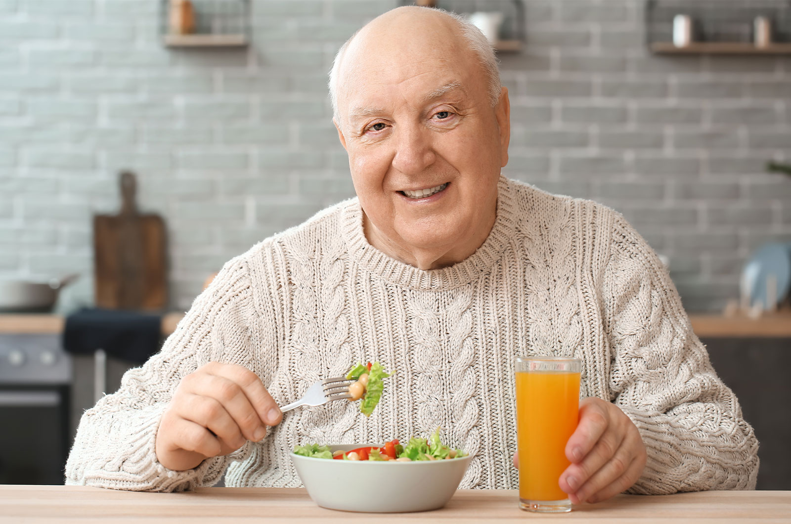 älterer Mann, der zu Hause ein gesundes Mittagessen zu sich nimmt