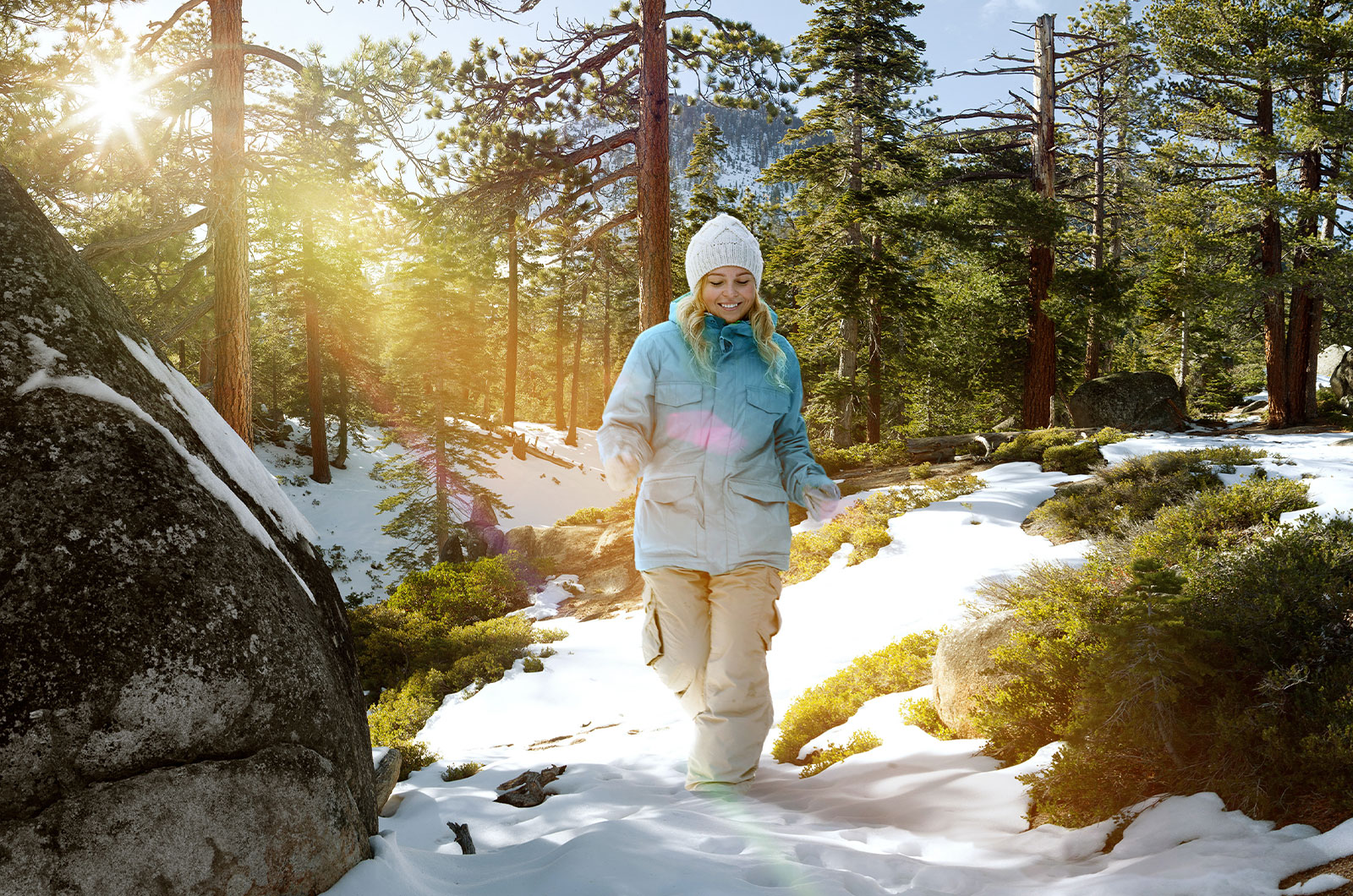 Bewegung bei Schnee und Kälte, junge, schwangere Frau stapft durch winterlichen Wald