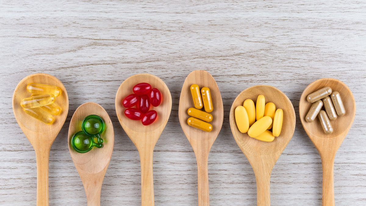 Mehrere Holzkochlöffel mit verschiedenen Vitamin-Tabletten in verschiedenen Farben